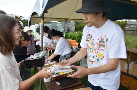ハナノキフェスで、オリジナルＴシャツを販売する松山ケンイチさん（右）＝南大隅町根占の花の木農場