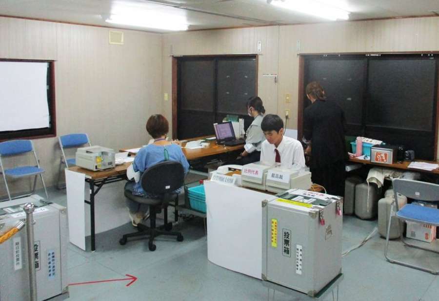 期日前投票所の運営を手伝う垂水高校生（中央）＝垂水市（市選管提供）