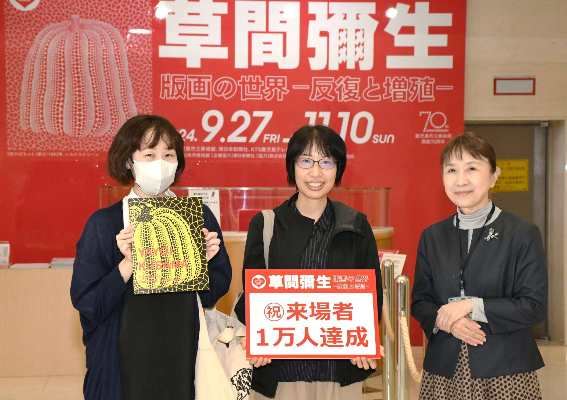 草間彌生展１万人目の入場者となった松下りえさん（左）＝２５日、鹿児島市立美術館
