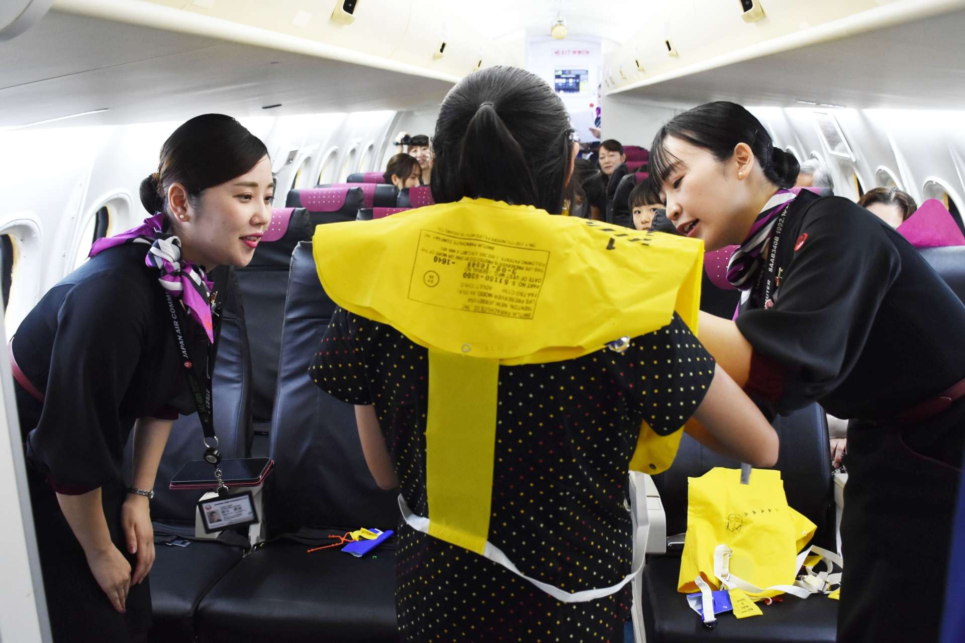 航空機の実物大模型の中で救命胴衣の着用法をアナウンスする参加者＝霧島市の鹿児島空港
