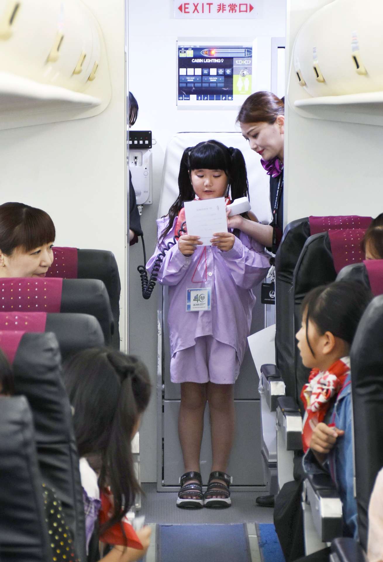 航空機の実物大模型の中で機内アナウンスに挑戦する「空の日フェスティバル」参加者＝霧島市の鹿児島空港