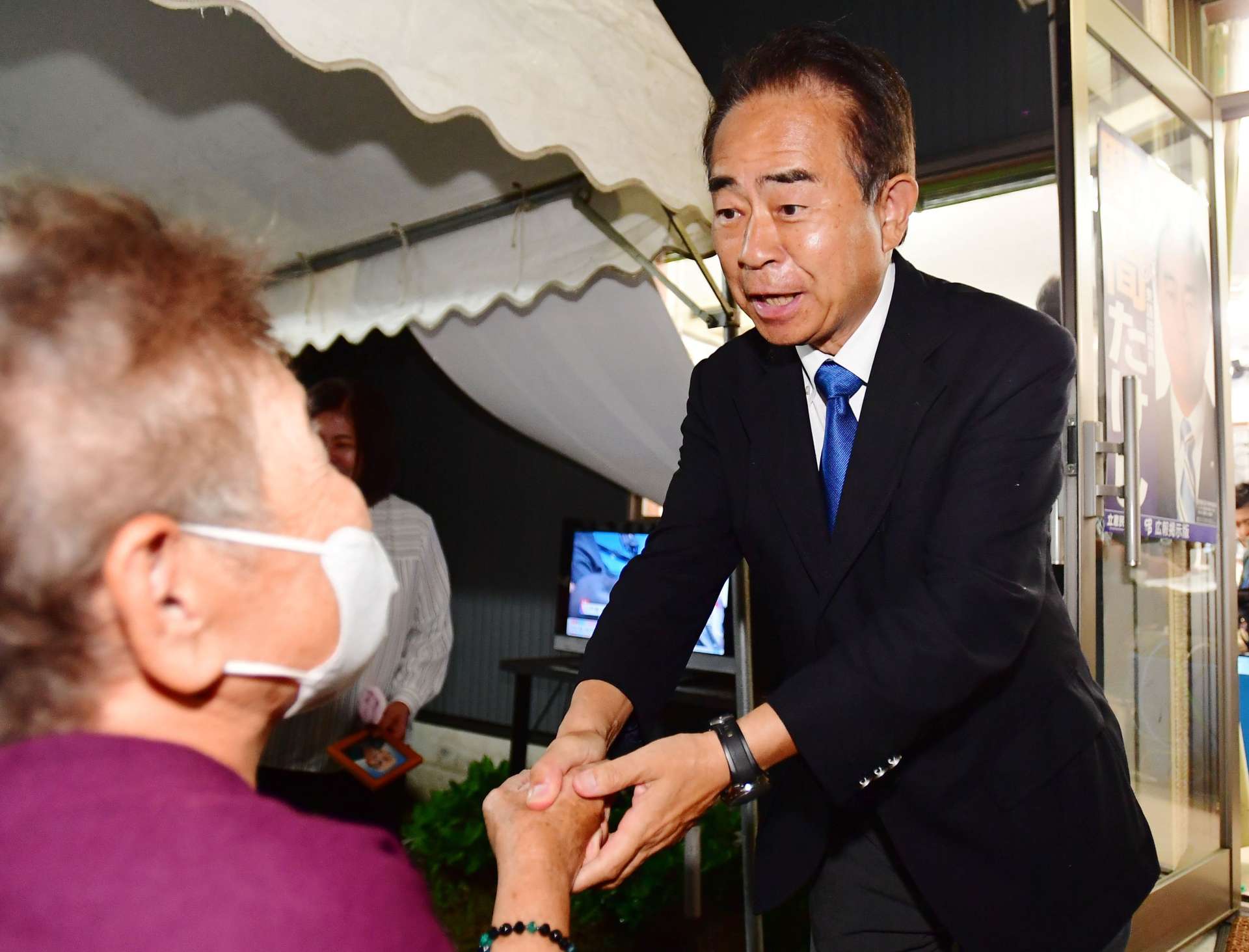 支持者と握手して喜び合う野間健さん＝２７日午後９時５６分、薩摩川内市御陵下町
