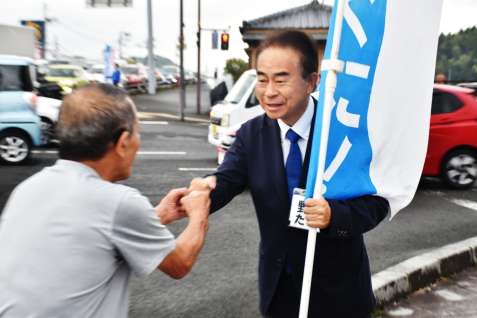 〈関連〉つじ立ちで支持者と笑顔でグータッチする野間健さん（右）＝２８日午前、薩摩川内市西向田町