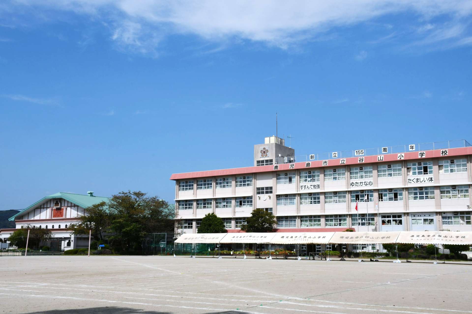 谷山小学校の校舎と緑の屋根が特徴的な講堂（左）＝１０月１１日、鹿児島市谷山中央１丁目