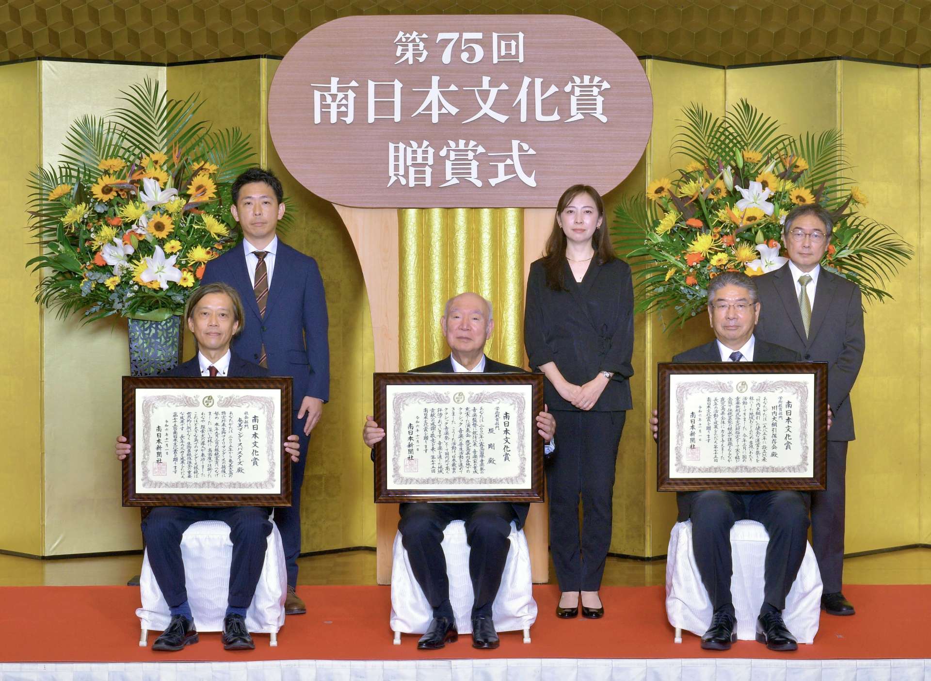受賞者の（左から）奄美マングースバスターズの松田維代表、堤剛さん、川内大綱引保存会の橋口知章会長。後列は介添人＝１日、鹿児島市の城山ホテル鹿児島