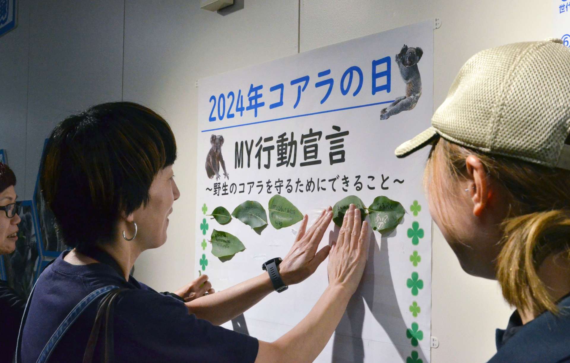 野生のコアラを守るための行動を書いたユーカリの葉を貼りつける参加者＝鹿児島市の平川動物公園