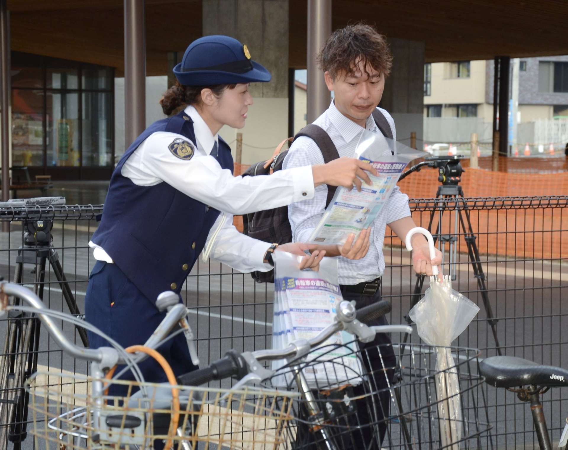 自転車利用者に道交法改正を周知する警察官＝１日、鹿児島市のＪＲ谷山駅