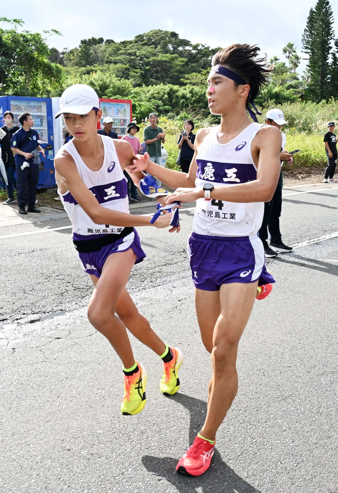 鹿工の６区・橋口（右）がアンカー桑野にたすきをつなぐ＝指宿市