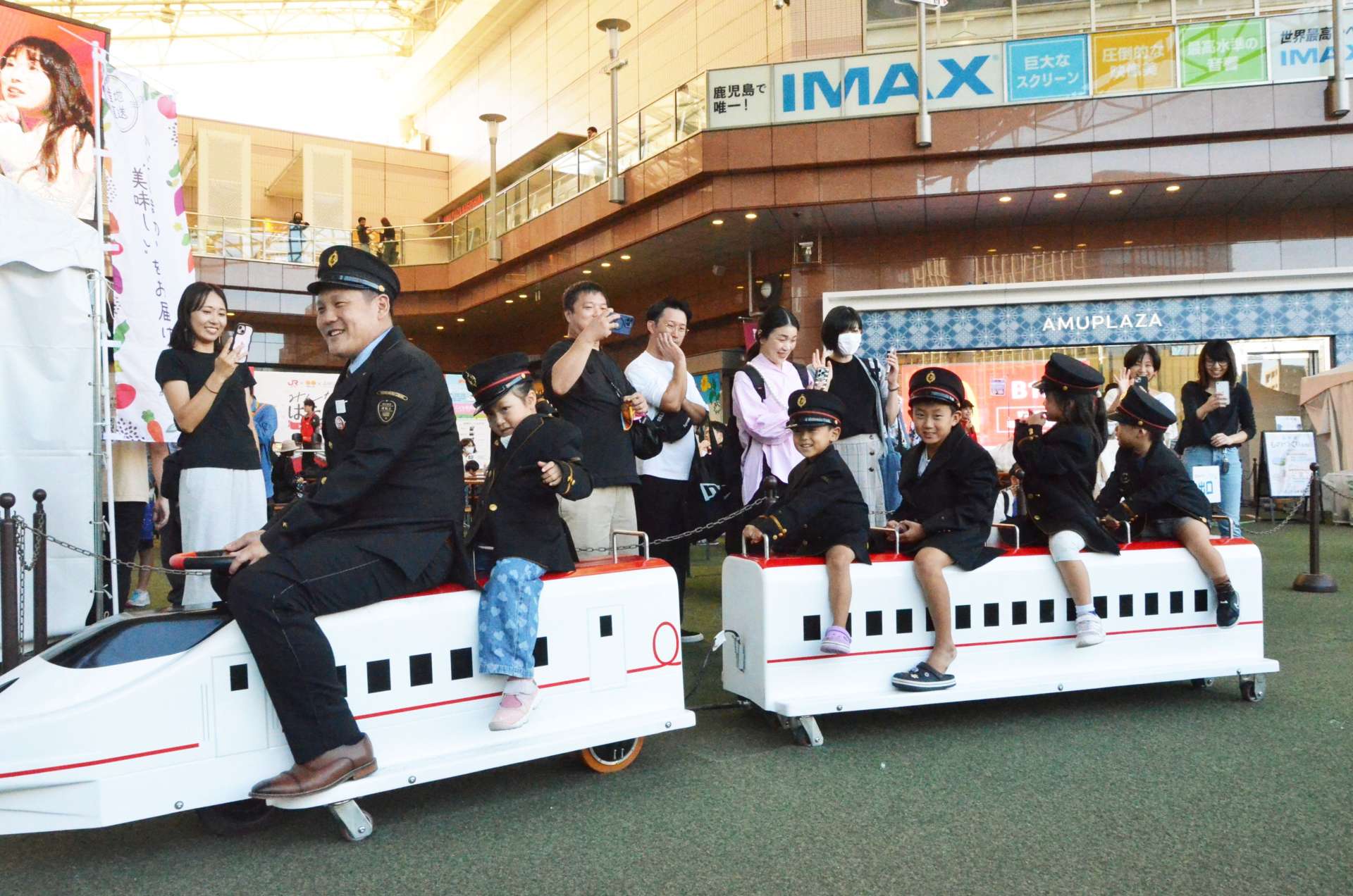乗務員の格好でミニトレインを楽しむ子どもたち＝３日、鹿児島市のアミュ広場