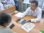 スマートフォンの使い方を説明する大浜郵便局の棈木博之局長（右）＝南大隅町根占山本