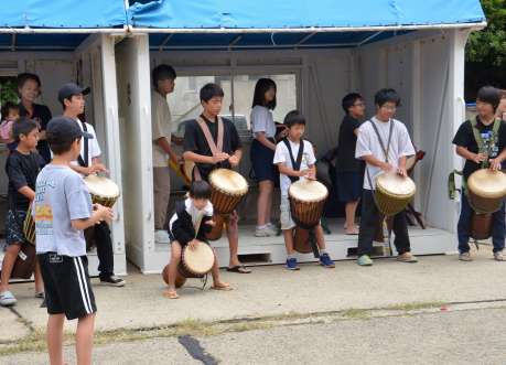 出港する船の乗客に向け、ジャンベの演奏を披露する児童生徒ら＝三島村硫黄島