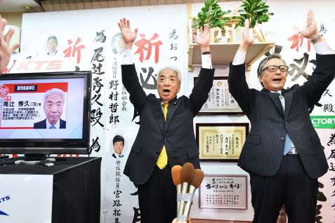 〈関連〉２０１９年７月の参院選で当選確実となり、集まった支持者らと万歳をして喜ぶ尾辻秀久さん（左）＝鹿児島市大黒町
