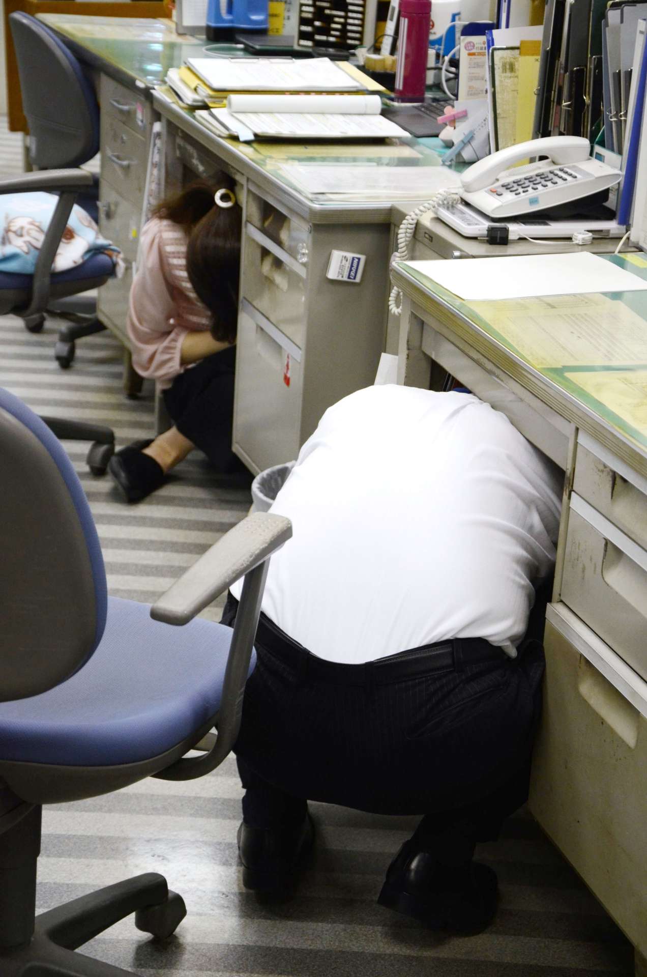 緊急地震速報で身の安全を確保する市職員＝５日、鹿児島市役所