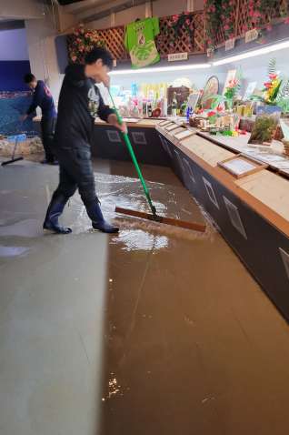 〈関連〉サザンクロスセンターに流れ込んだ水を掃き出す関係者＝９日午前９時半ごろ、与論町立長（町岡安博さん提供）