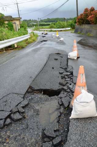 雨水でめくれあがったとみられる道路のアスファルト＝１０日午後２時４５分ごろ、与論町那間
