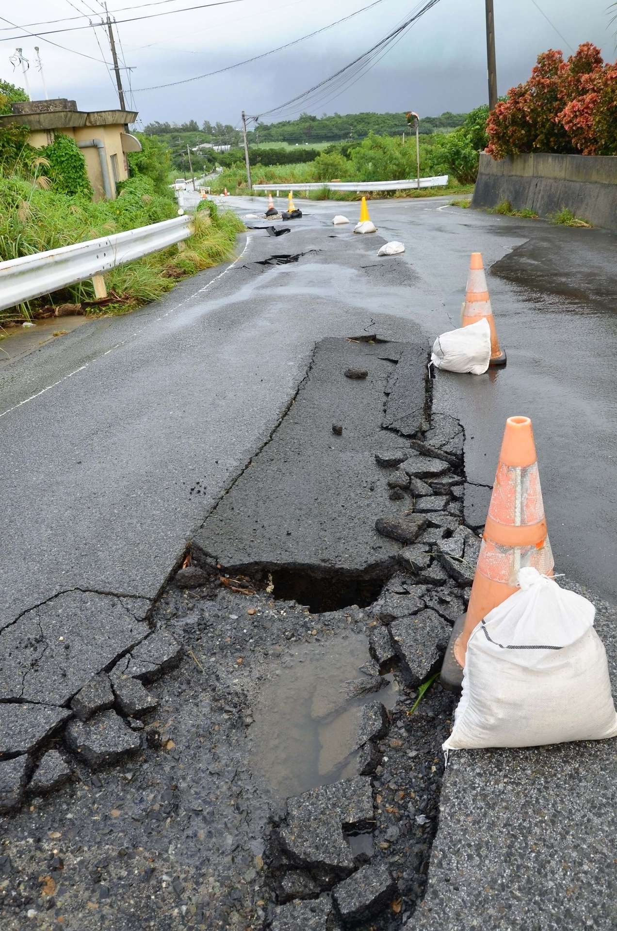 雨水でめくれあがったとみられる道路のアスファルト＝１０日午後２時４５分ごろ、与論町那間