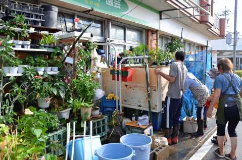 浸水で使えなくなった商品棚を運び出す町民ら＝１０日午後３時２０分ごろ、与論町茶花
