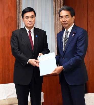 江藤拓農相（右）に引き継ぎ資料を手渡す小里泰弘氏＝１２日、農林水産省