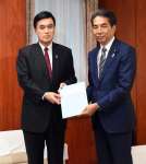 江藤拓農相（右）に引き継ぎ資料を手渡す小里泰弘氏＝１２日、農林水産省