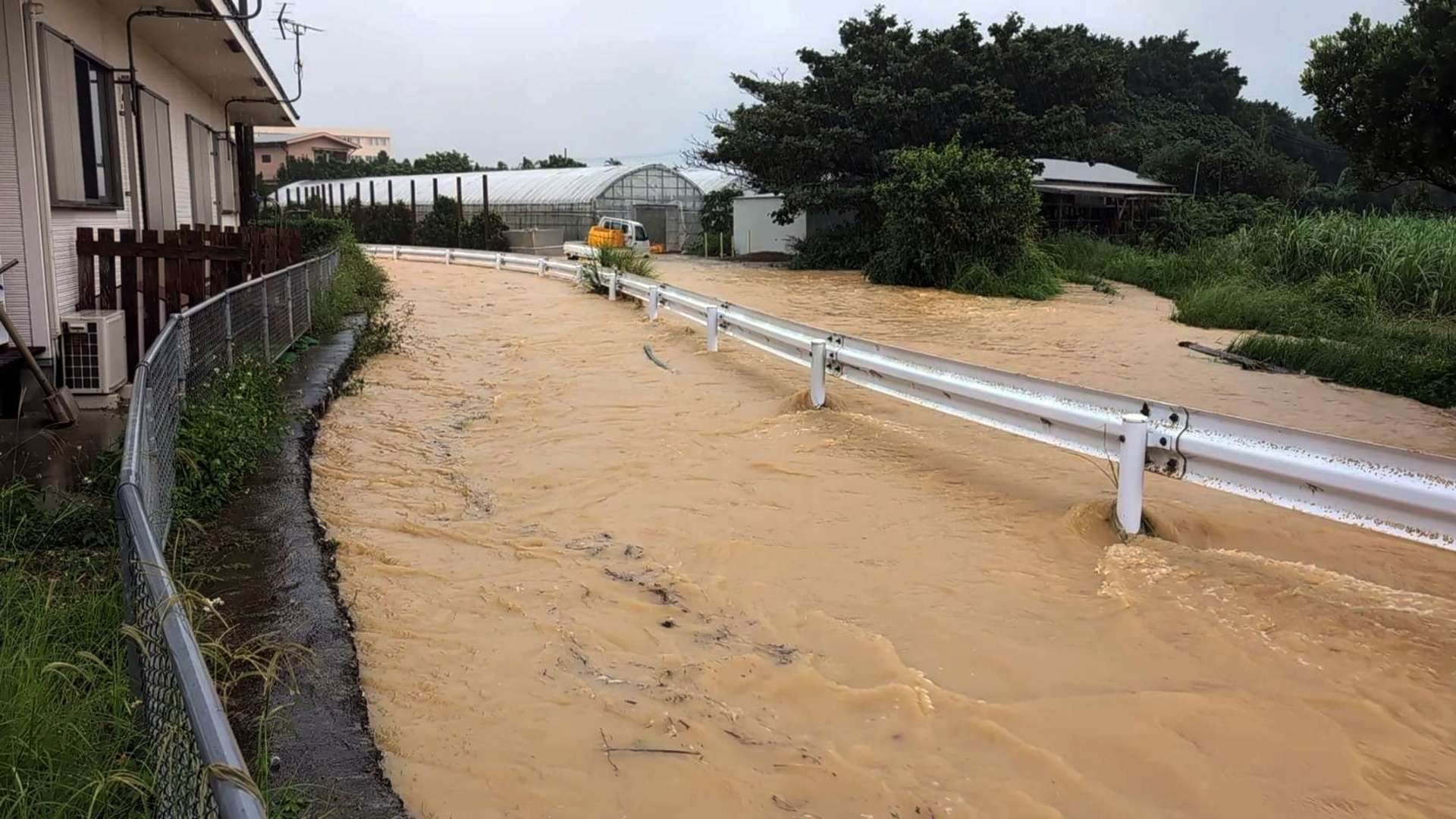 排水路（ガードレールから左）があふれ、冠水した町道。車が一時立ち往生した＝与論町茶花（同町提供）