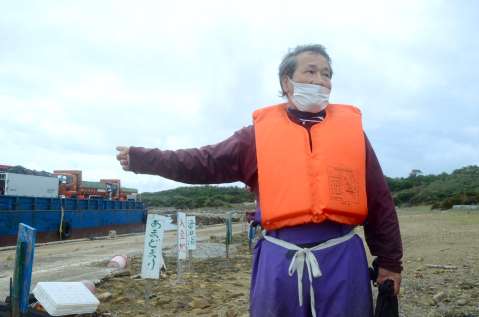 葉山港に停泊する工事関係船舶の前で話をする浜田純男さん＝西之表市馬毛島、１５日午後２時半ごろ