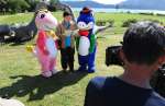 池田湖や開聞岳をバックに、地元のマスコットキャラクターと撮影に臨む主演の内藤剛志さん＝９月、指宿市のえぷろんはうす池田