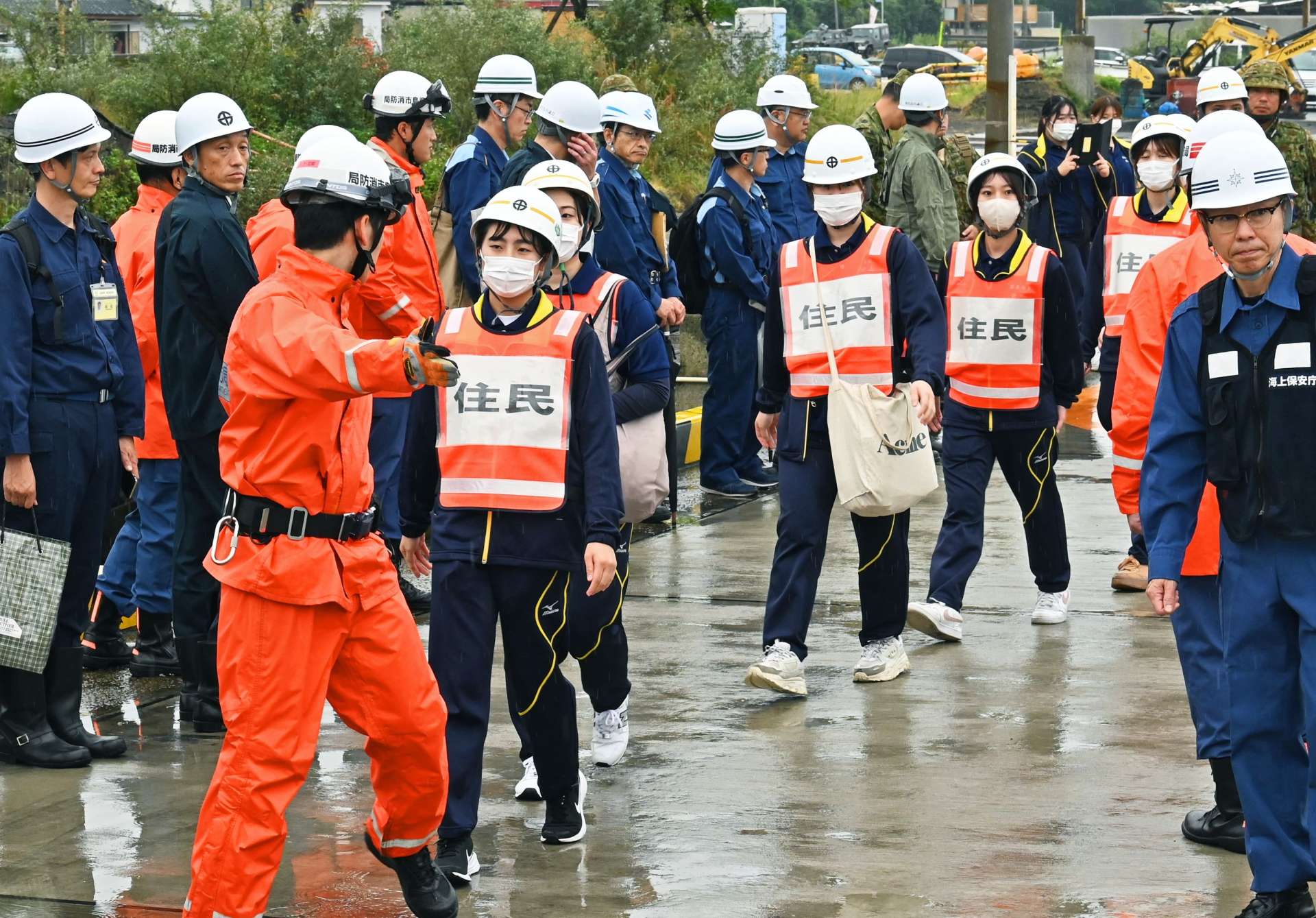 消防職員に誘導され赤水港に向かう住民役の学生ら＝１６日午前１０時２２分、鹿児島市桜島赤水町
