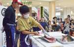 カンパチの解体を実演する小段彰人さん（手前）＝１６日、鹿児島市のオプシアミスミ