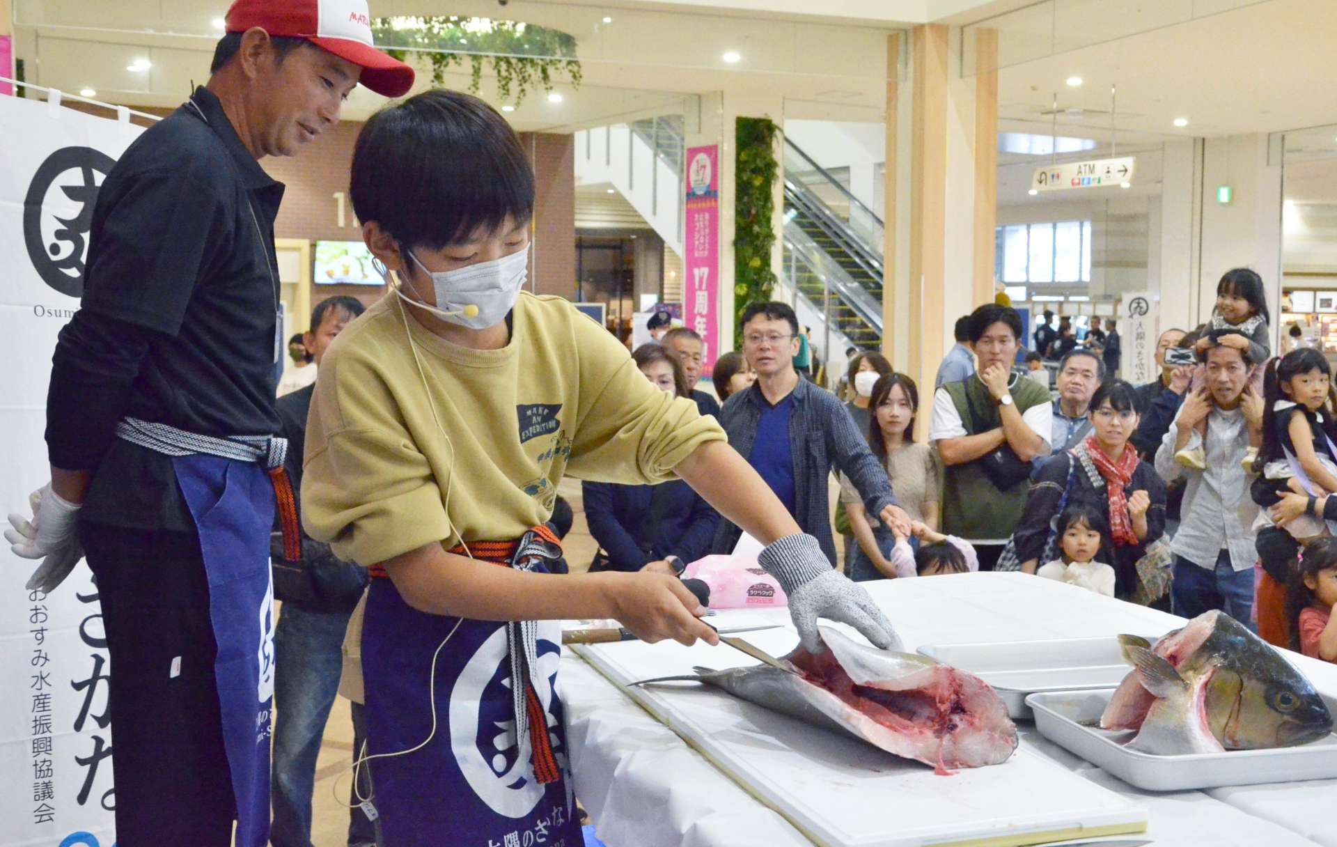 カンパチの解体を実演する小段彰人さん（手前）＝１６日、鹿児島市のオプシアミスミ
