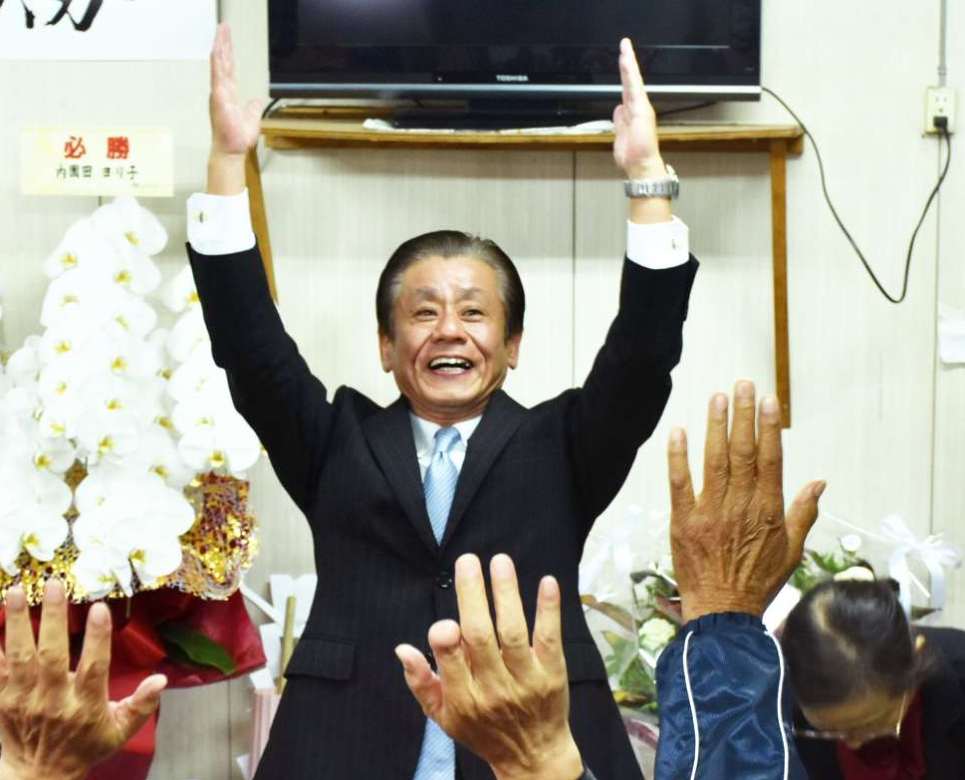 支援者と喜びを分かち合う橋本欣也氏（中央）＝１７日午後１０時２０分ごろ、伊佐市大口里