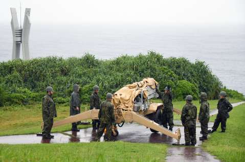 〈関連〉伊仙町の犬田布岬で無人偵察機の発射台を準備する自衛隊員。左奥は戦艦大和の慰霊碑＝１０月２４日