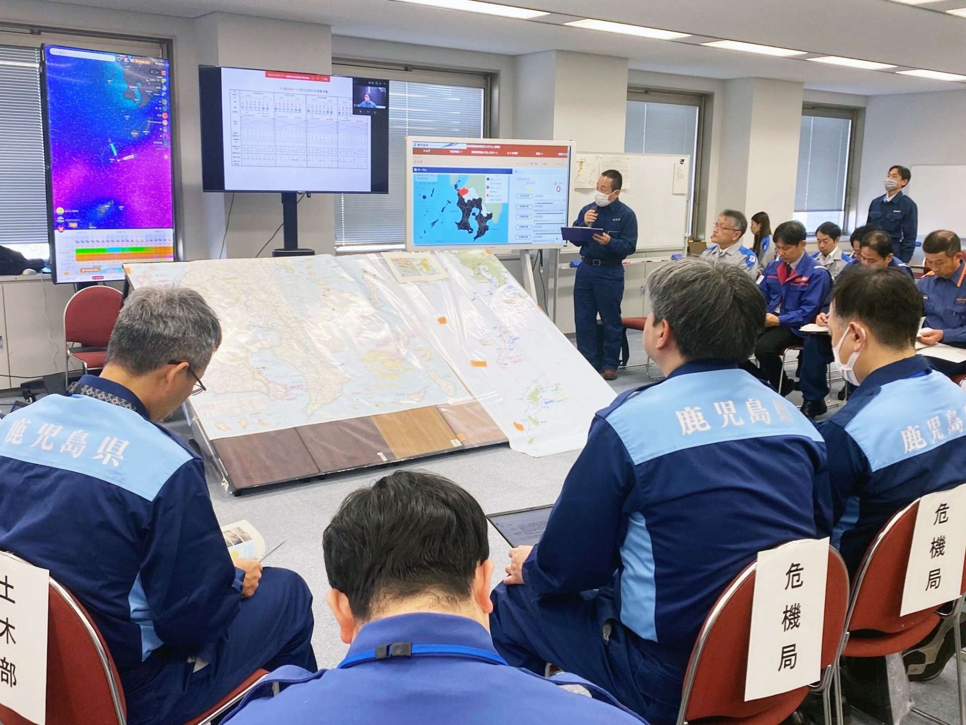 離島防災訓練で、災害発生後の気象状況について説明する鹿児島地方気象台の職員ら＝２０日、鹿児島県庁
