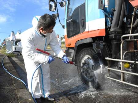 国道３号沿いで車両を消毒する県職員＝２０日午前９時半、出水市野田町下名
