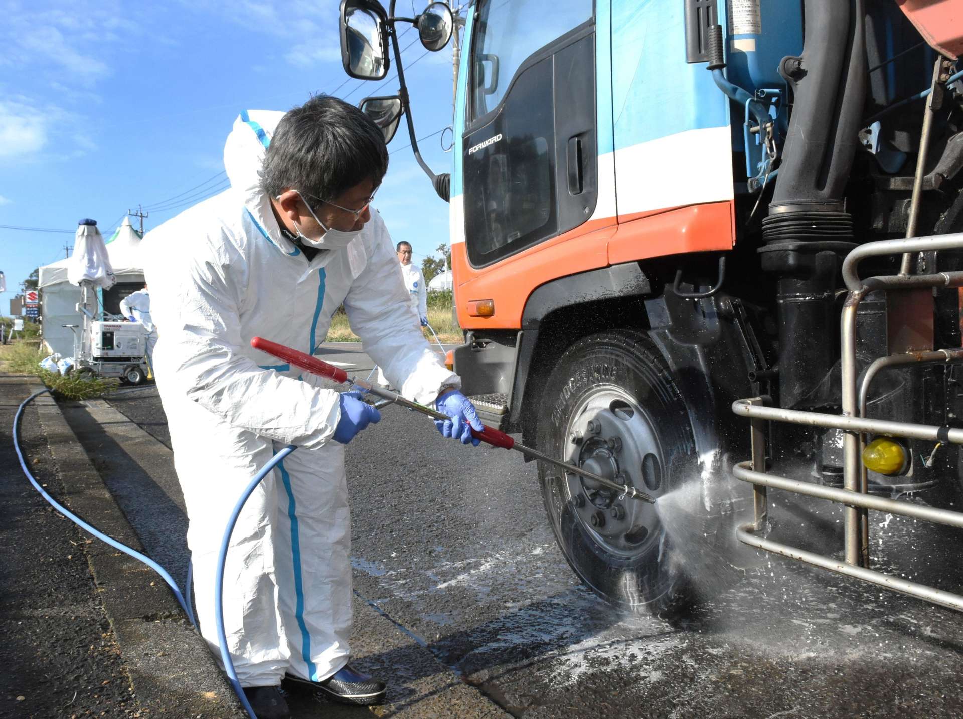 国道３号沿いで車両を消毒する県職員＝２０日午前９時半、出水市野田町下名