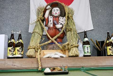 供え物と一緒に鎮座する田の神＝１９日午後、さつま町求名の下狩宿公民館