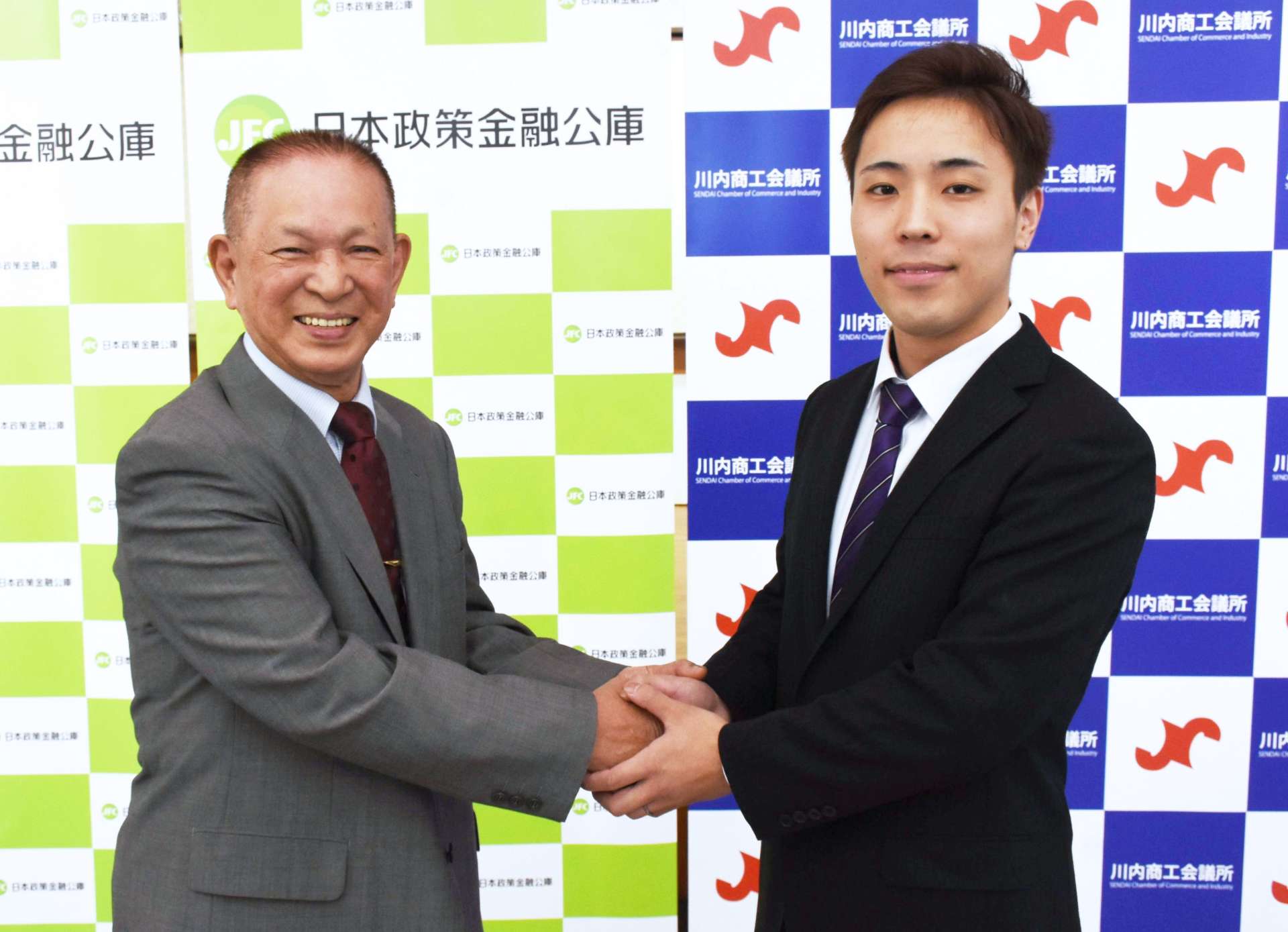 成約式で握手する山本和幸さん（左）と田ノ上崚さん＝２１日、薩摩川内市の川内商工会議所