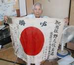 出征時の寄せ書き入り国旗と軍隊手帳を持つ野元俊雄さん＝霧島市牧園