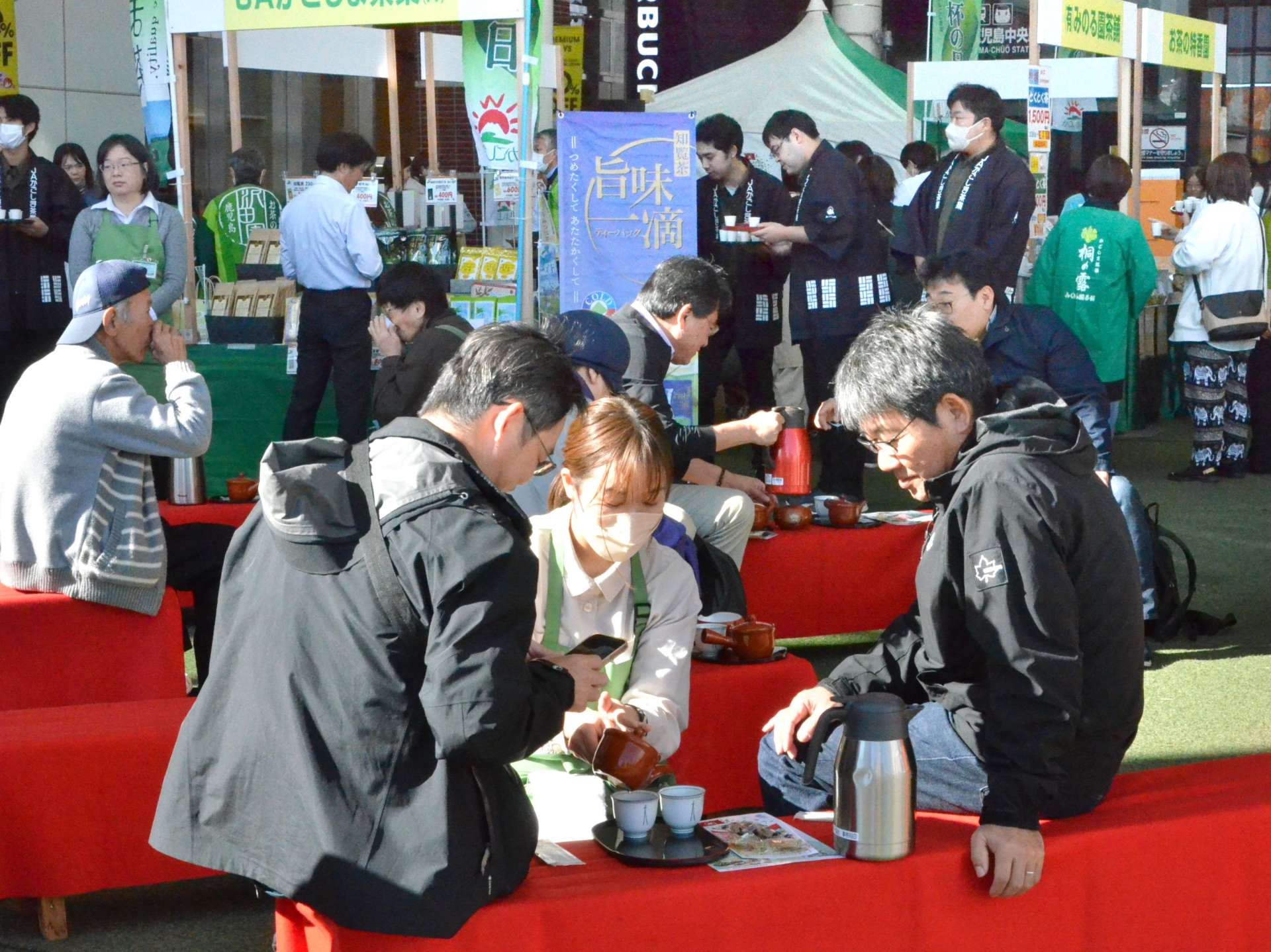 急須で入れるかごしま茶を楽しむ来場者＝２３日、鹿児島市の鹿児島中央駅前アミュ広場