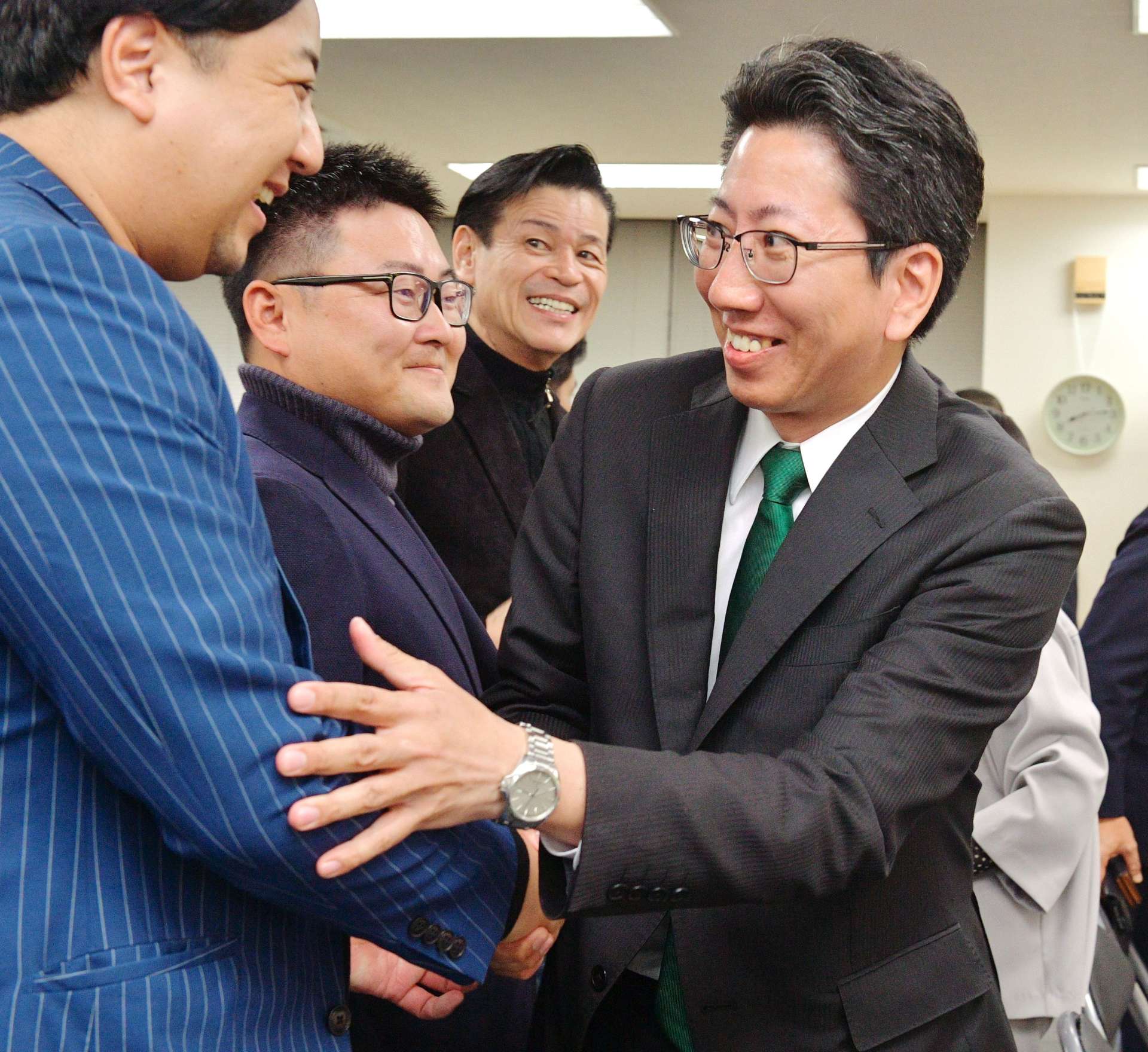 当選を確実にし、支持者と笑顔で握手する下鶴隆央さん＝２４日午後８時１３分、鹿児島市東千石町