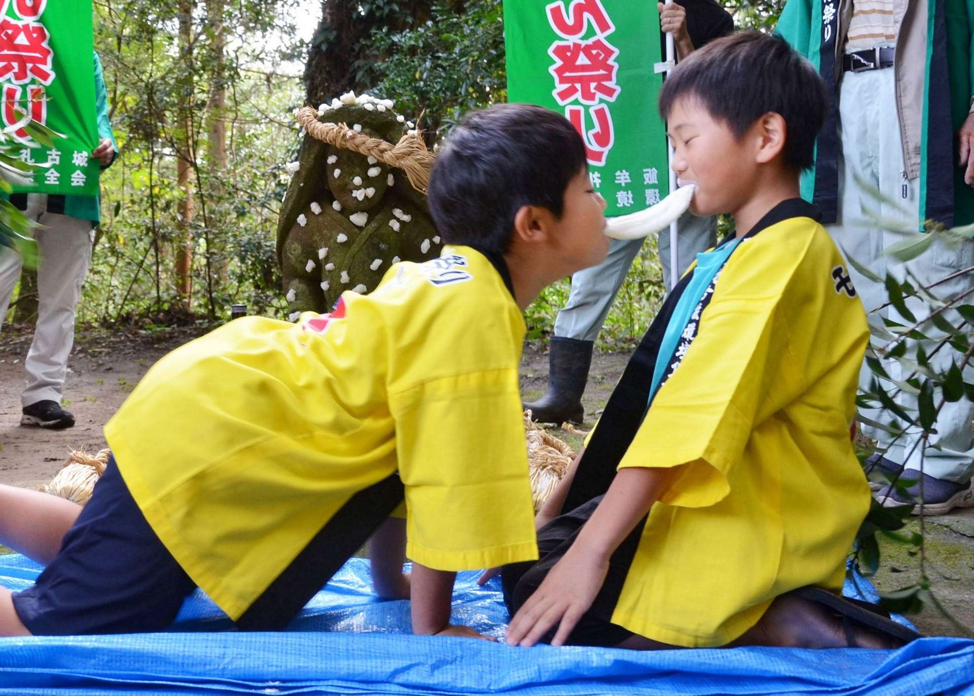四つんばいになって、駆け引きしながら長餅を引っ張り合う子どもたち＝日置市伊集院町古城の大山祇神社
