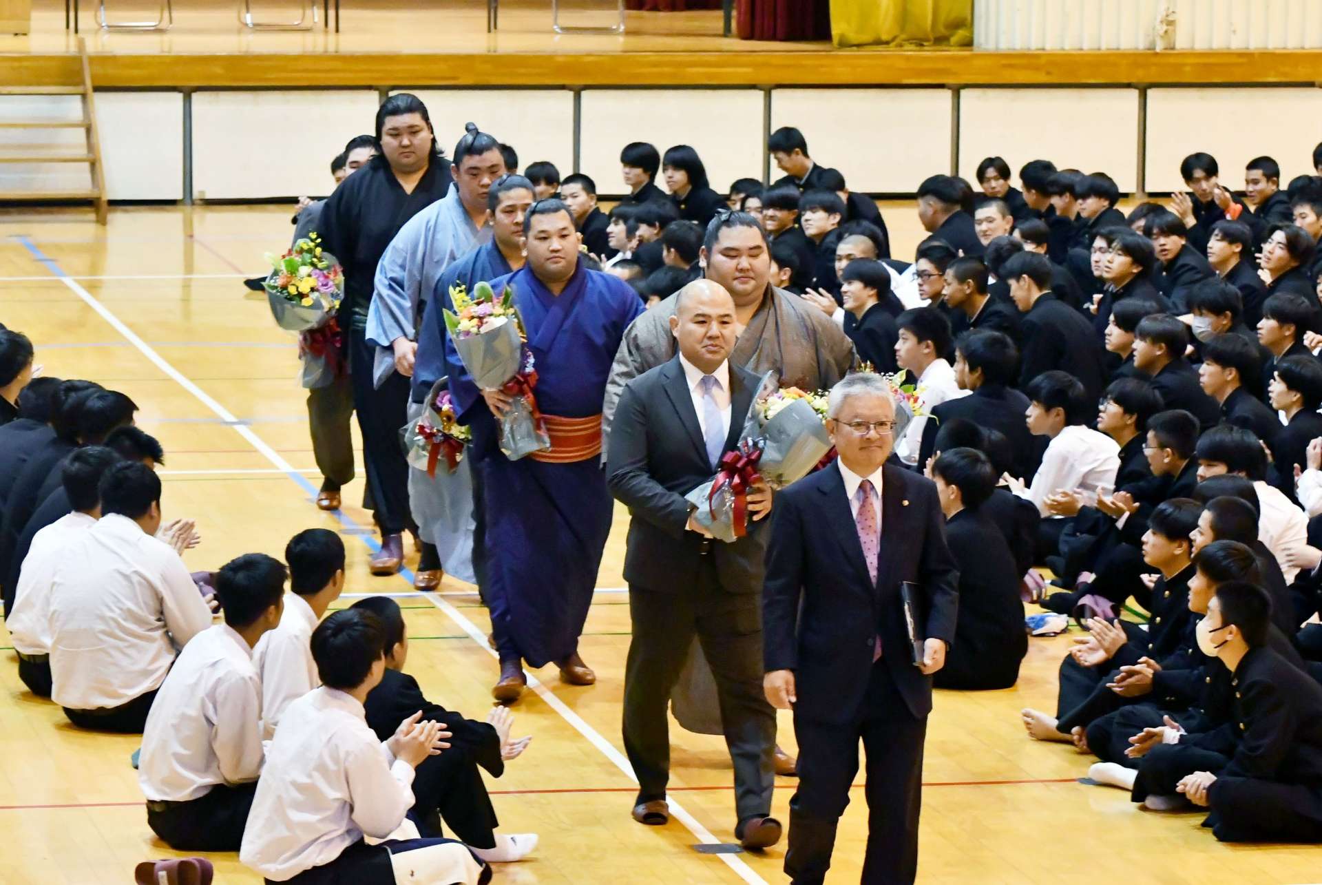 生徒に拍手で送り出される現役力士の大奄美ら＝鹿児島市の鹿児島商業高