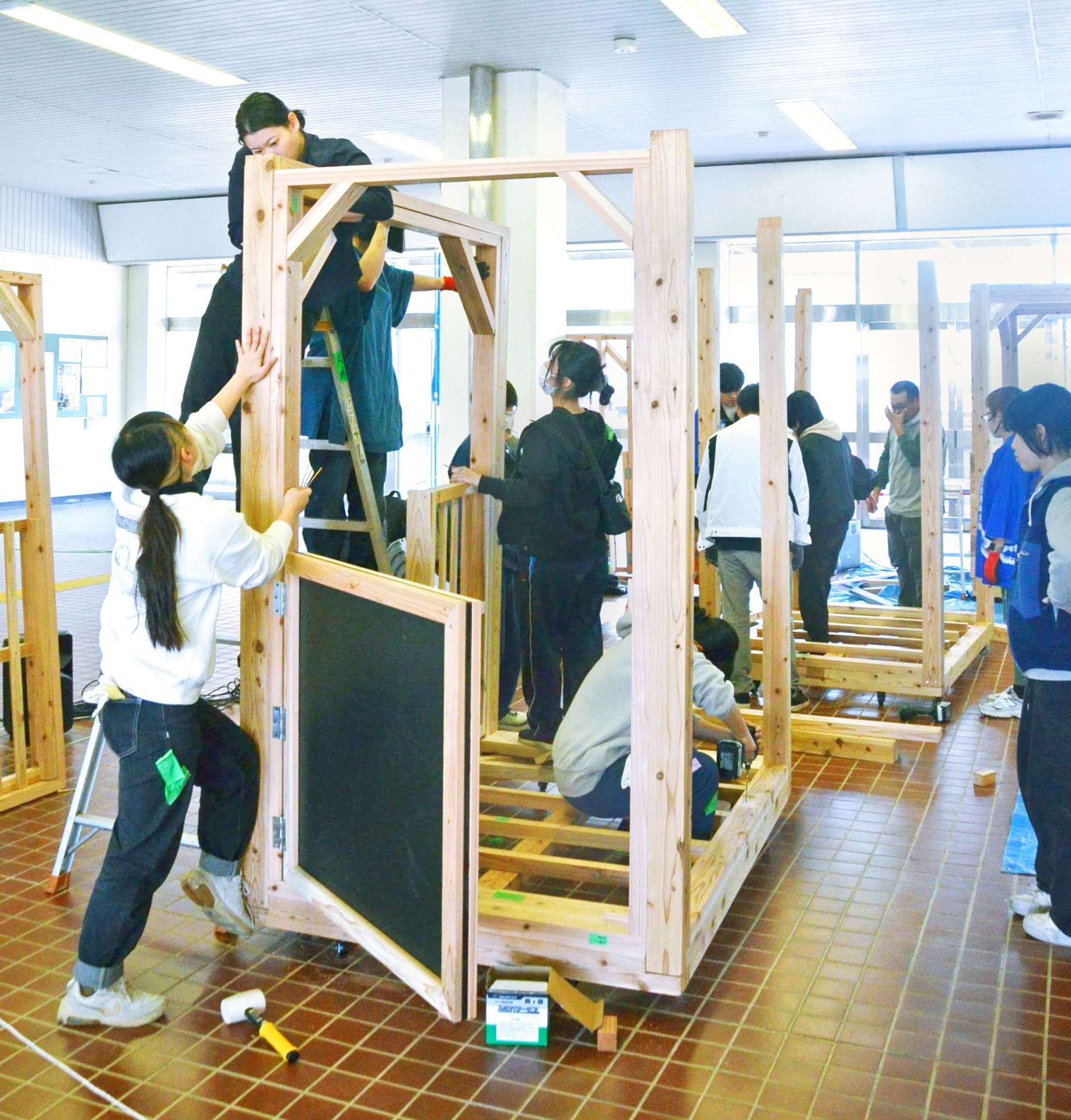 宮崎県産スギ材で木製列車を組み立てる都城高専の学生ら＝都城市松元町