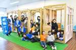 西都城駅１階コンコースに木製列車を完成させた都城高専の学生と県建築士会都城支部員ら＝都城市松元町