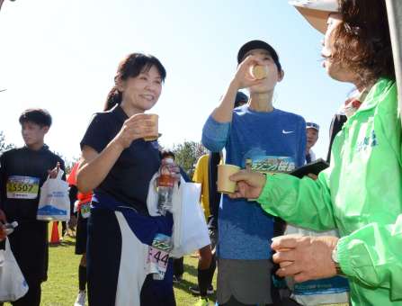 走り終わった後、桜島小みかんジュースを飲むランナー＝１日、鹿児島市桜島横山町
