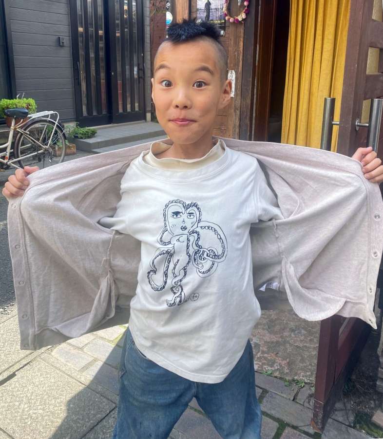自作の絵をプリントしたＴシャツを見せるポヨヨン太郎さん＝鹿児島市名山町