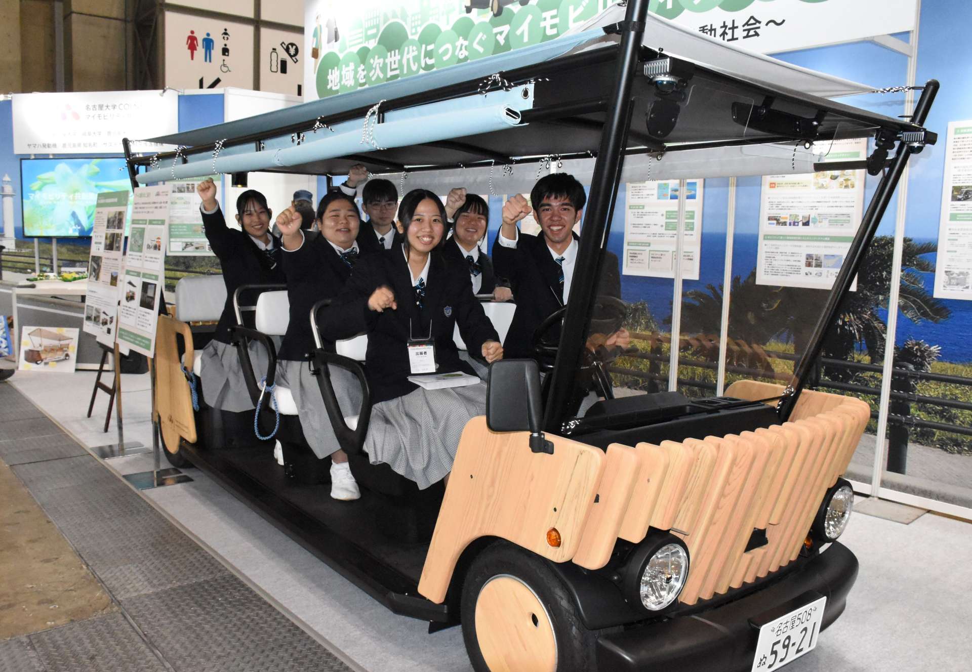 デザインに携わった車両に乗り笑顔を見せる沖永良部高校３年生＝５日、東京・有明の東京ビッグサイト