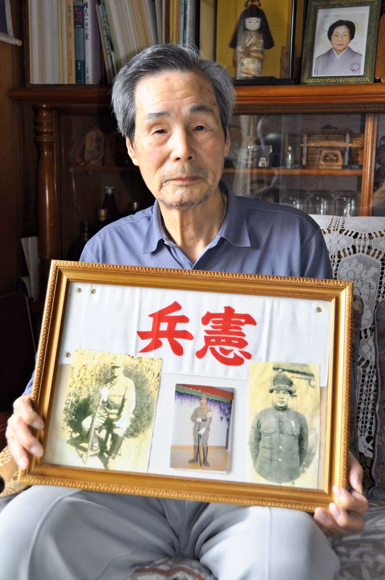 憲兵時代の写真を持つ前田盛次さん＝鹿児島市西陵１丁目