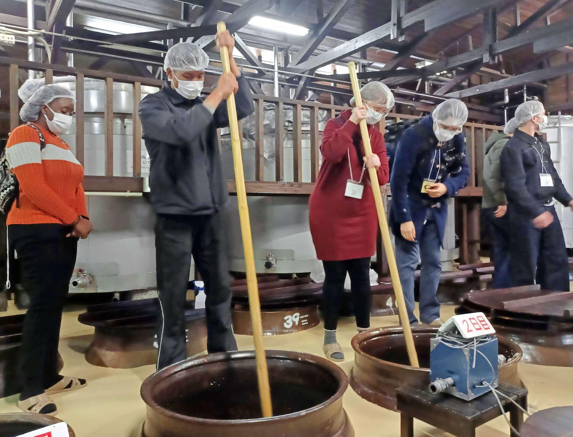 焼酎蔵で櫂入れを体験するＡＬＴや留学生ら＝７日、霧島市の霧島町蒸留所