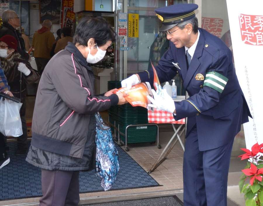 拉致事件のチラシを手渡す日置警察署の小林正樹署長＝１１日、日置市東市来の江口蓬莱館