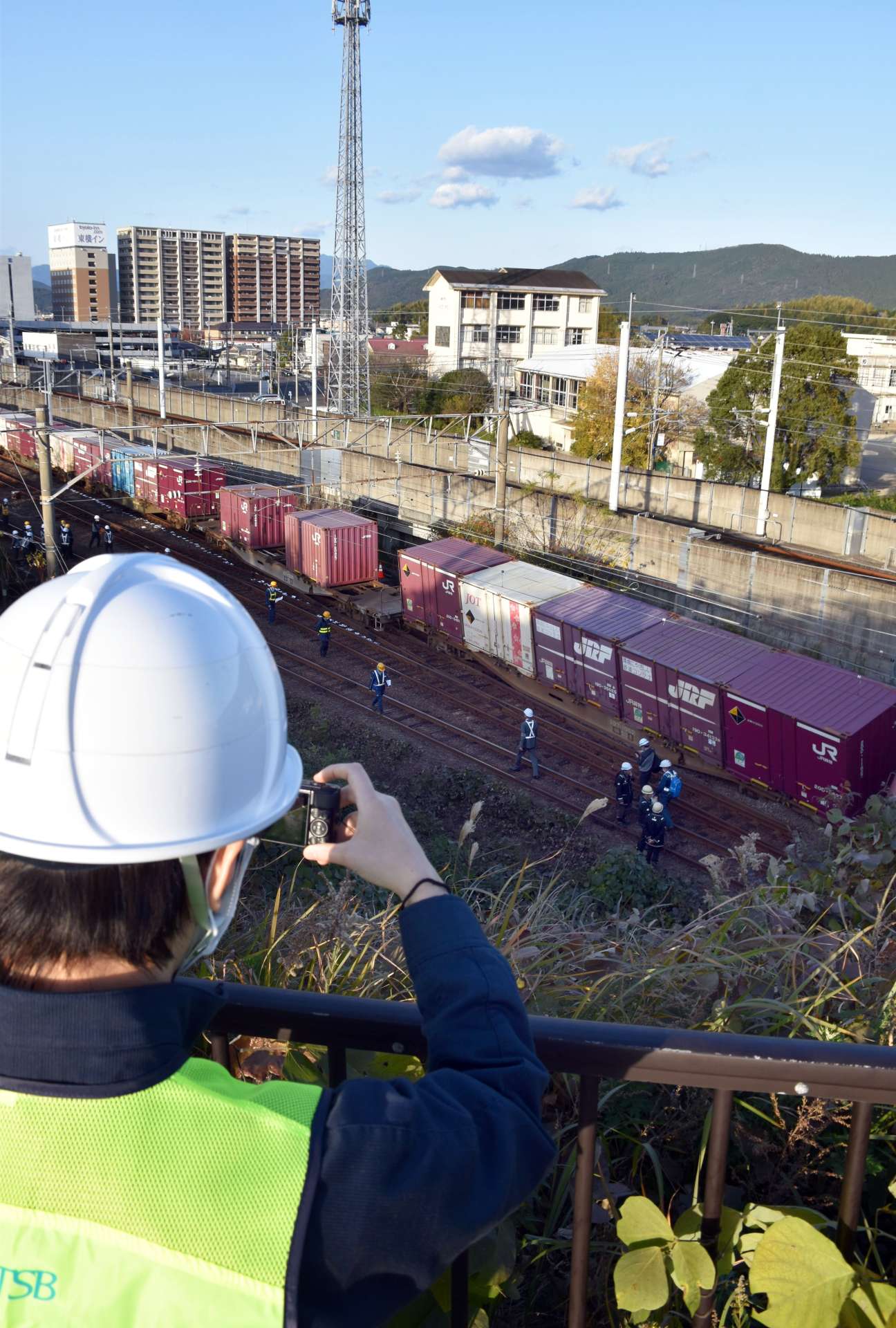 脱線した列車を撮影する運輸安全委員会の鉄道事故調査官＝１２日、薩摩川内市